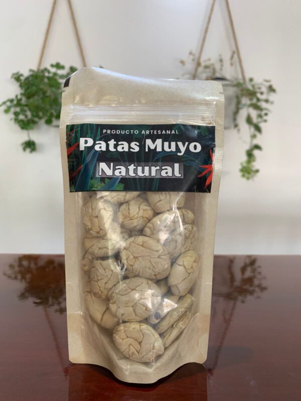 Bolsa de "Patas Muyo Natural", un producto artesanal amazónico en empaque ecológico con ventana transparente que muestra las semillas tostadas en su interior.