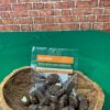 Bolsa de "Patas Muyu con Chocolate" de la marca Raíces del Napo, un snack artesanal de semillas de macambo tostadas cubiertas con chocolate negro, presentado en un recipiente rústico sobre un fondo verde.